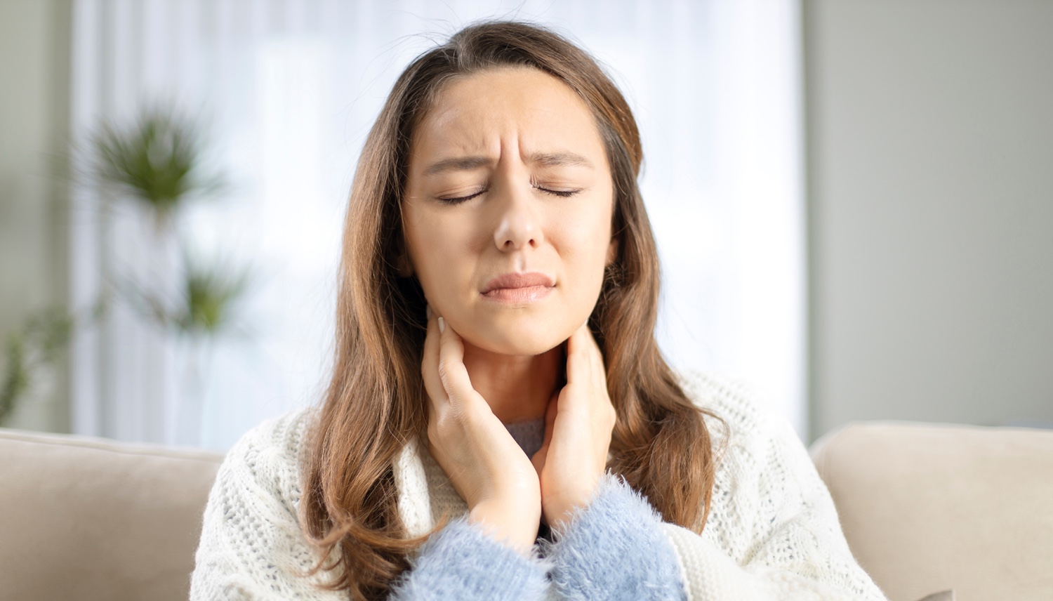 Young woman touching painful neck, sore throat for flu, cold and infection