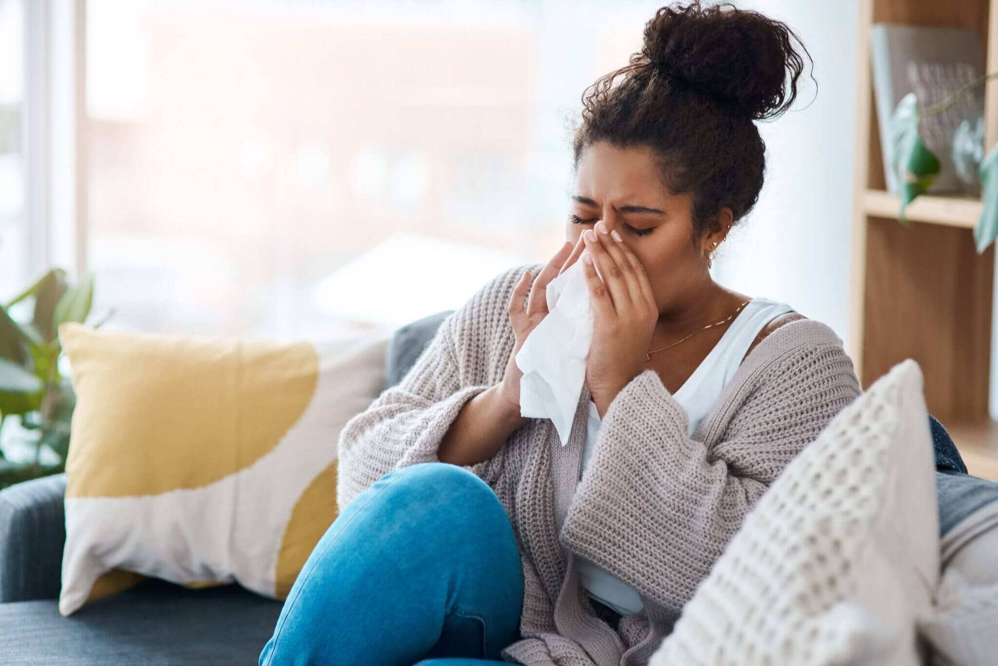 woman sneezing into a tissue